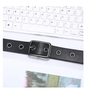 Black leather belt detail featuring metal buckle and eyelets, versatile accessory close up view