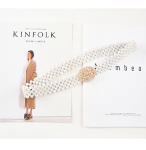 Close-up detail of white multi-strand pearl elastic waist belt with sparkling rhinestone buckle.
