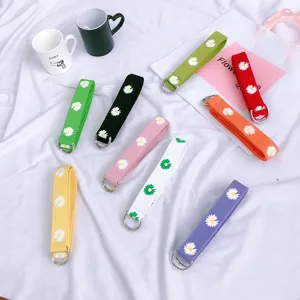 Cintura in tela con margherite stampate e fibbia a doppio anello, accessorio colorato per uso quotidiano.