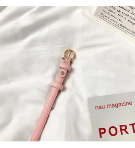 Women slim pink leather dress belt with elegant gold horseshoe buckle detail flat lay