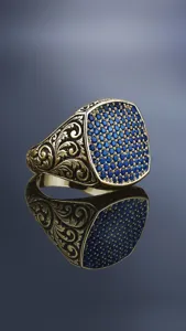 Close-up detail van vintage heren zegelring met blauwe stenen en ingewikkeld graveerwerk.