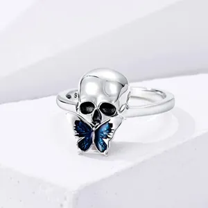 Close-up detail shot of gothic style silver skull ring featuring blue enamel butterfly charm.