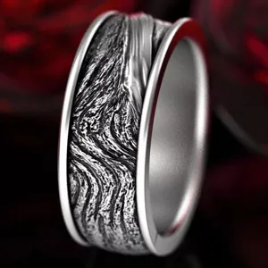 Close-up detail of vintage punk wide metal ring with intricate carved texture and polished edges.
