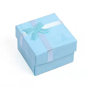 Helles blaue quadratische Schmuckgeschenkbox mit weisser Schleife fuer kleine Ohrringe Ringe