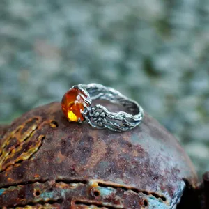 Detailed close-up of a vintage Thai silver floral ring featuring a glowing amber stone.