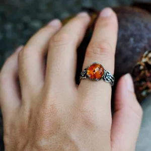 Detailed view of a vintage Thai silver ring featuring a natural amber stone with floral band.