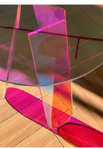 Primo piano dettagliato di un tavolino in acrilico trasparente iridescente con riflessi arcobaleno.
