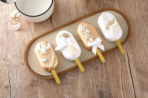Primer plano de postres mini decorativos con acabado dorado y blanco en una bandeja.