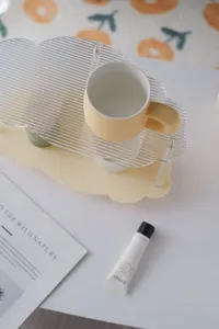 Acrylic desktop storage rack with ceramic cup, clear wavy cloud design for vanity decor.