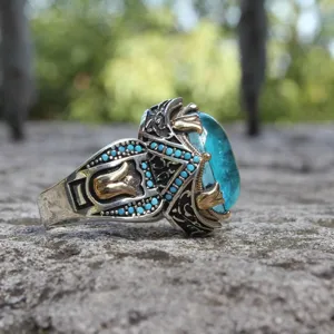 Gros plan détaillé de la bague vintage bicolore sculptée avec pierre bleue et perles.