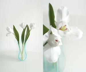 Nahaufnahme künstlicher weißer Tulpen in moderner transparenter Acryl-Vase als Tischdeko.