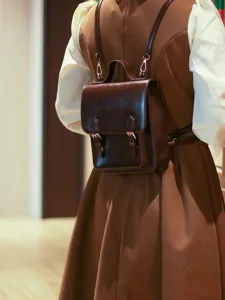 Vue de détail d'un mini sac à dos marron élégant au design rétro avec poignée supérieure.