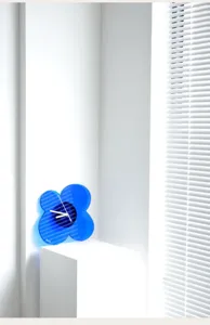 Detail shot of the modern Klein blue acrylic flower wall clock showcasing its unique silhouette.
