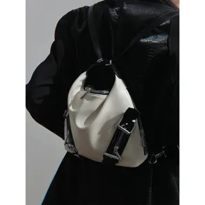 Detail shot of a stylish silver convertible backpack, showcasing its unique straps and metal zippers.