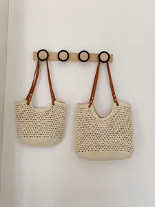 Vista dettagliata della borsa tote in paglia intrecciata con manici in pelle, estiva.