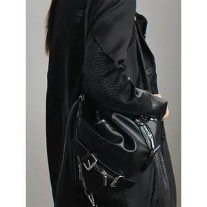 Close-up detail of black leather multi-zipper shoulder bag featuring metallic buckle.