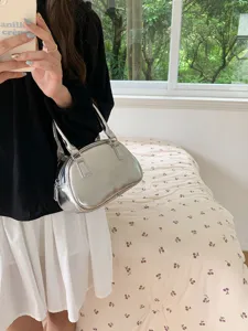 Detail view of stylish silver metallic handbag, fashion shoulder bag showcasing shiny finish.