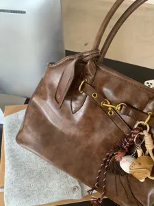 Vintage brown commuter tote bag for women with chic hardware and baseball charm details.