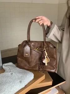 Retro brown PU leather handbag detail, showcasing hardware, texture, and hanging charms.