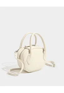Detail view of the elegant mini beige bowling handbag, highlighting smooth texture and hardware.