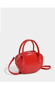 Red leather bowling bag detail showing smooth glossy finish and sturdy top handles for women.