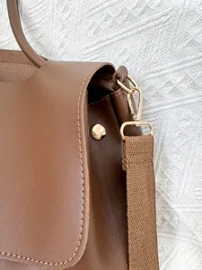 Nahaufnahme der braunen Leder-Umhängetasche mit Fokus auf Textur, Beschläge und den breiten Gurt.