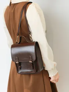 Détail de petit sac à dos style collège rétro, mini cartable marron en cuir pour femme.