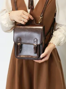Détail du sac à dos rétro marron, avec brides à boucles et style collège élégant.