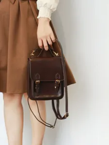Gros plan détaillé d'un mini sac à dos en cuir vintage marron avec boucles et poignée.