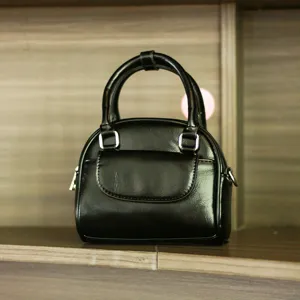 Black small shell handbag detail showing classic retro top handle and silver hardware accent.