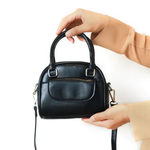 Details of the black PU leather dome handbag showing front pocket, hardware and shoulder strap.