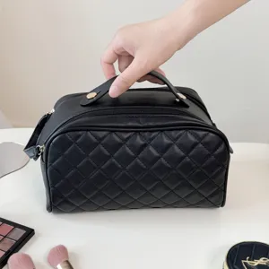 Black quilted cosmetic bag with top handle and large capacity interior storage design.