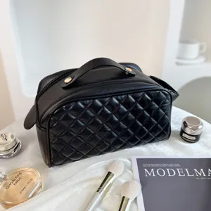 Black quilted cosmetic bag, travel toiletry organizer with handle and zipper closure detail.
