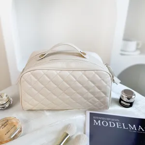 White quilted cosmetic bag detail view, premium travel makeup pouch with double zippers and handle.