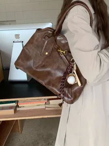 Close-up detail of retro brown leather shoulder tote bag, casual daily commuting fashion style.