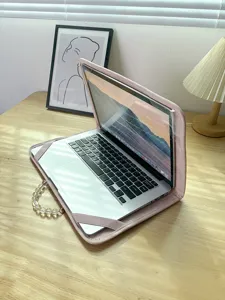 Detaillierte Nahaufnahme der rosafarbenen Laptoptasche mit Perlenhenkel auf Holztisch.