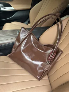 Detailed view of the brown soft leather tote bag showcasing its unique heart charm and chain.