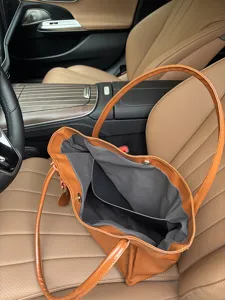 Detailed close-up view of the soft leather tote bag interior lining and heart charm pendant.