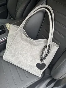 Grey soft leather tote bag detail showcasing unique heart pendant and dark chain accessory.