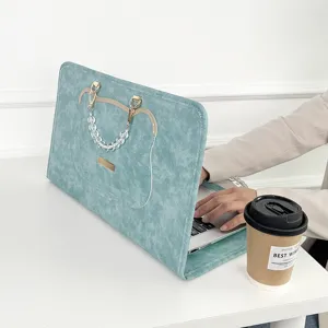 Detailaufnahme der türkisfarbenen Laptoptasche mit Perlenhenkel auf einem hellen Schreibtisch.