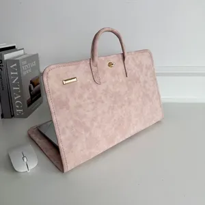 Detailed view of the pink suede laptop sleeve with handle and gold clasp on a clean desk.