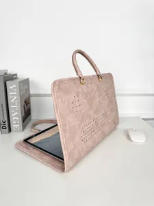 Vue détaillée de la housse d'ordinateur en cuir rose avec poignée, trous d'aération et texture.