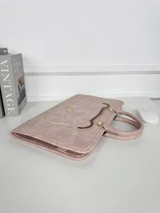 Vue détaillée de la pochette d'ordinateur en cuir rose avec texture et quincaillerie.