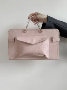 Dettaglio custodia per laptop rosa con manico in perle e tasca frontale elegante.