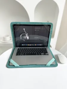 Detailansicht der weichen tealblauen Laptophülle mit Gummibändern auf weißem Schreibtisch.