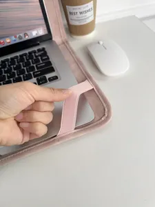 Nahaufnahme eines rosa Samt-Laptopschutzes mit Gummiband auf einem sauberen weißen Schreibtisch.