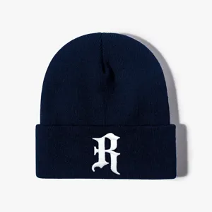 Close-up of navy blue knit beanie featuring white gothic letter R embroidery detail.