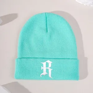 Mint green knit beanie detail shot, featuring white Gothic letter R embroidery on the front cuff.