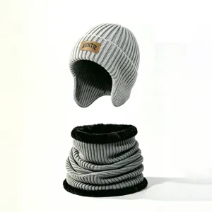 Conjunto de gorro de punto gris con orejeras y calentador de cuello de felpa, detalle invierno.