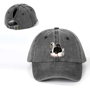 Detalle de gorra de béisbol gris lavado con estampado de gato negro y hebilla metálica.